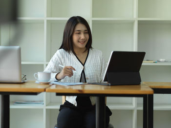 Young businesswoman using laptop while sitting at office