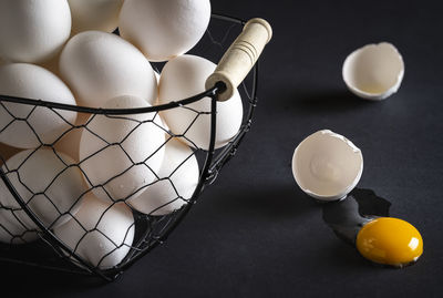 Close-up of broken egg by basket on table