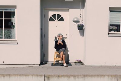 Full length of woman sitting outside building