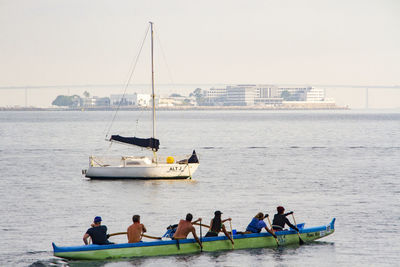 People in boat sailing on sea against clear sky