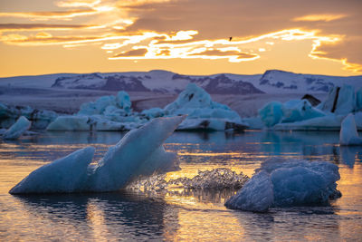 Scenic view of icebergs on lake against sky during sunset