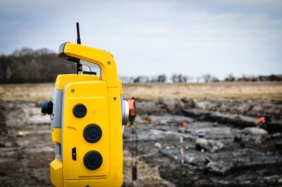 Surveying level on field against sky