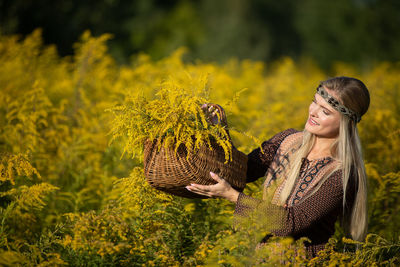 Portrait of young woman standing amidst plants