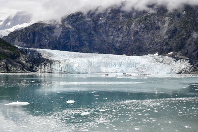 Ancient glacier and foggy dramatic sky in alaska ocean bay
