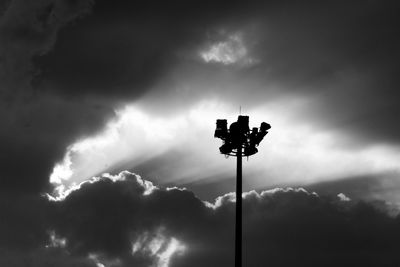 Low angle view of floodlight against cloudy sky