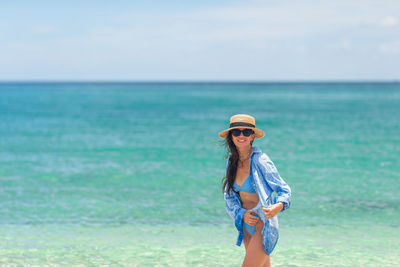 Full length of woman standing at beach against sky