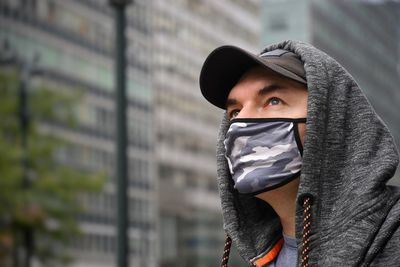 Close-up of man wearing flu mask looking away while standing outdoors