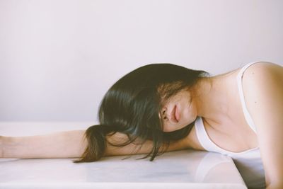 Sad woman lying down on table against white background