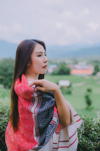 Beautiful young woman standing against the sky