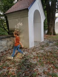 Boy standing by house against building