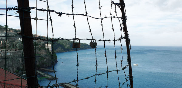 Scenic view of sea against sky seen through fence