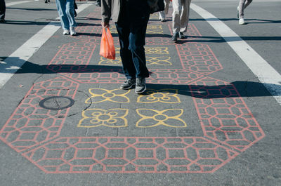 Low section of people walking on floral pattern footpath