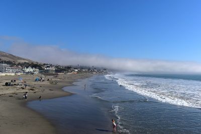 People on beach against clear blue sky