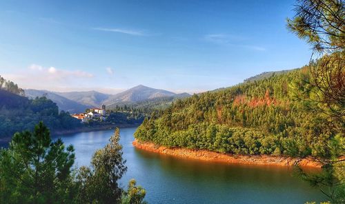 Scenic view of river by mountains against sky