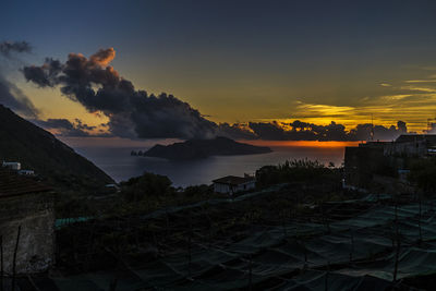 High angle view of buildings by sea against sky during sunset