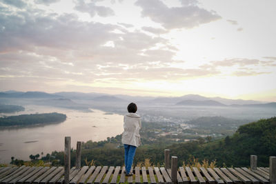 Rear view of man standing on mountain against sky