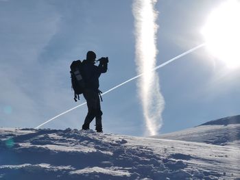 Low angle view of man standing on snow against sky