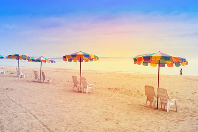 Deck chairs and parasols on beach against sky