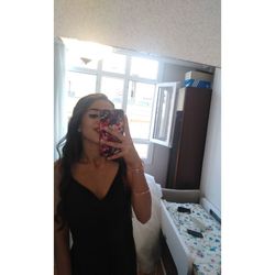 Portrait of woman holding window at home