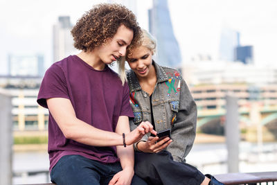 Young couple using mobile phone in city