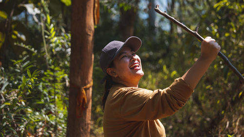 Smiling woman holding branch outdoors