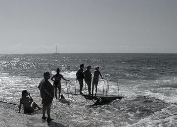 People at beach against clear sky during summer