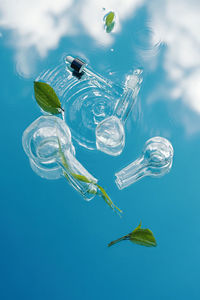 Various laboratory glassware with organic plants lies on a water background with blue sky reflection