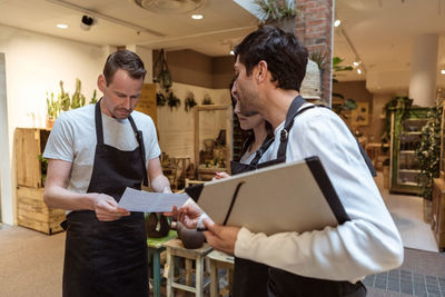Male owner discussing over document with colleagues at store