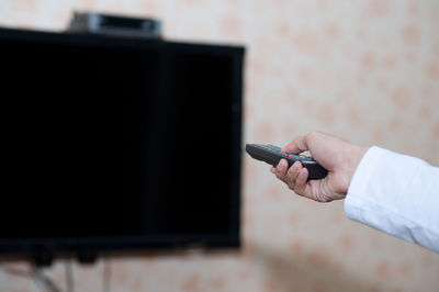 Midsection of man holding camera at home