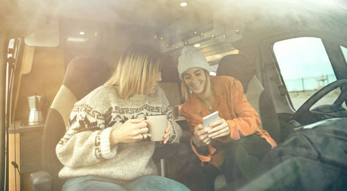 Rear view of friends standing in car