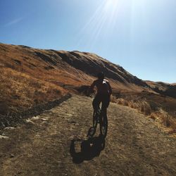 Rear view of man riding bicycle on mountain