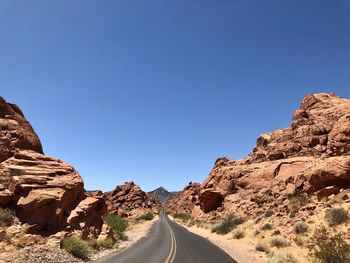 Road amidst rocks against clear blue sky