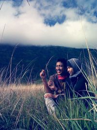 Young woman smiling while sitting on land against sky