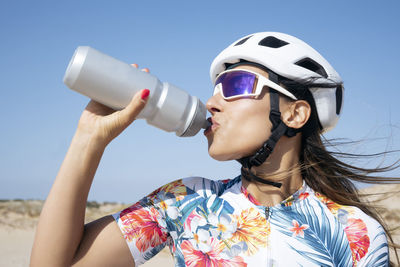 Thirsty cyclist drinking water under sky