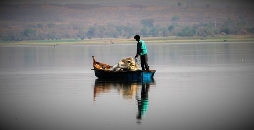 Fisherman standing in boat on river
