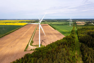 Aerial view of a large three blade industrial wind turbine generating electricity in a wind farm