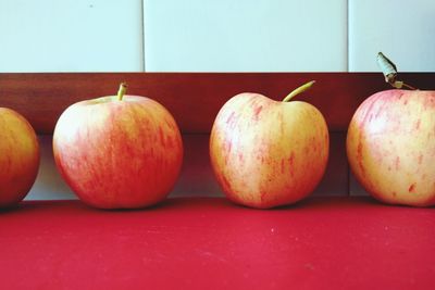 Close-up of apples on table against wall