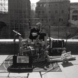 Man sitting on street against buildings in city