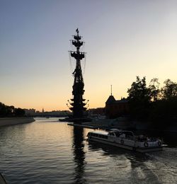 Silhouette boats in river against sky during sunset