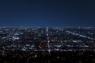 Drone shot of illuminated cityscape and beautiful stars shining in dark sky