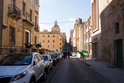 Cars on road in city against sky