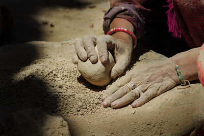 Cropped hands of woman holding rock on land