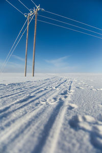 Snow covered landscape against blue sky