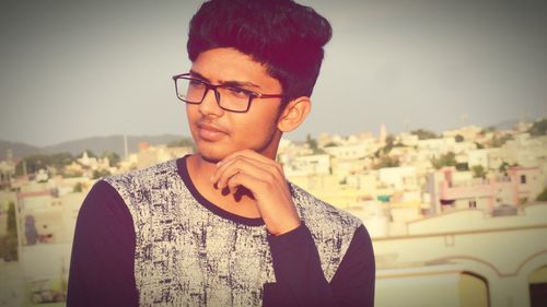 Close-up of thoughtful young man wearing eyeglasses in city