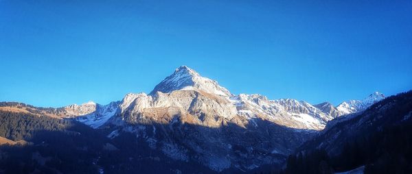 Scenic view of snowcapped mountains against clear blue sky