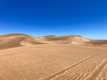 Scenic view of desert against clear blue sky