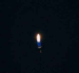 Close-up of lit candle against black background