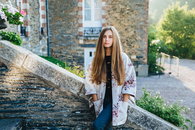 Portrait of young woman standing against built structure