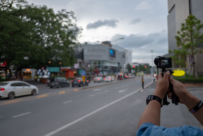 Man photographing car on city street