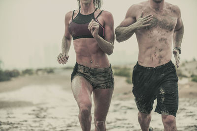 Midsection of couple running on sand